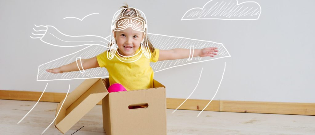 Petite fille jouant à l'avions avec un carton de déménagement - la bellenergie