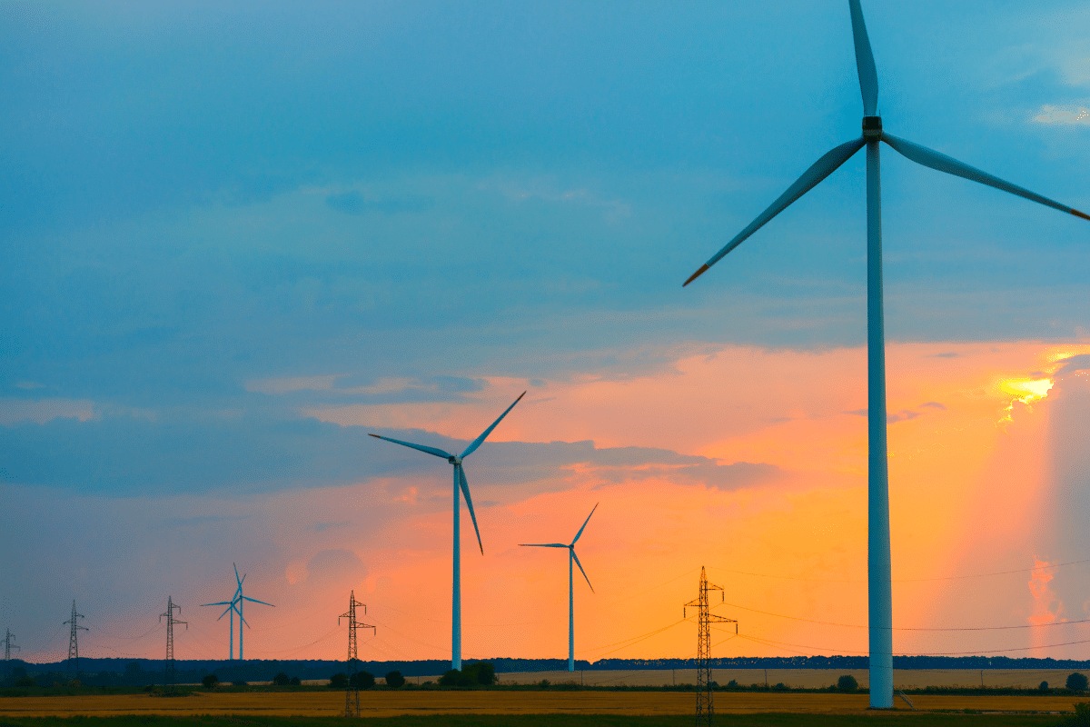 Plusieurs éolienne avec un soleil couchant et un ciel orange