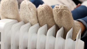 Personnes avec des chaussettes de laines épaisses se réchauffant les pieds sur un radiateur