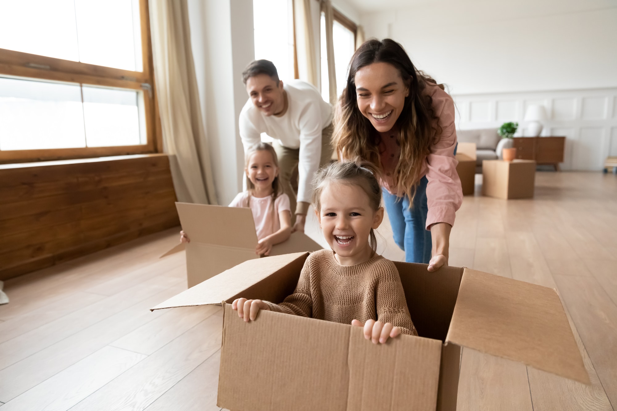Parents et enfants jouant avec joie avec des cartons de déménagement - la bellenergie