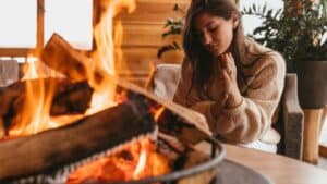 Jeune femme près d'un feu de bois - Comment bien choisir votre mode de chauffage - la bellenergie